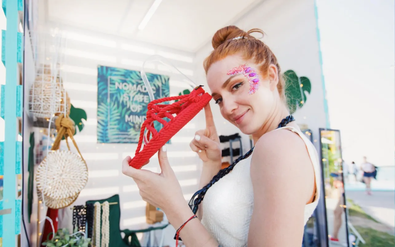 Festival vendor presents a red crocheted accessory at her market booth
