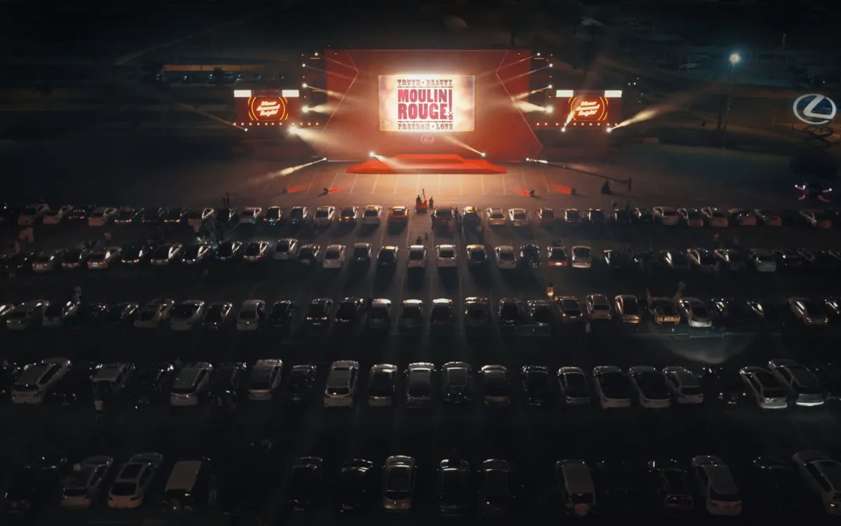 Rows of parked cars face the outdoor Moulin Rouge cinema screen