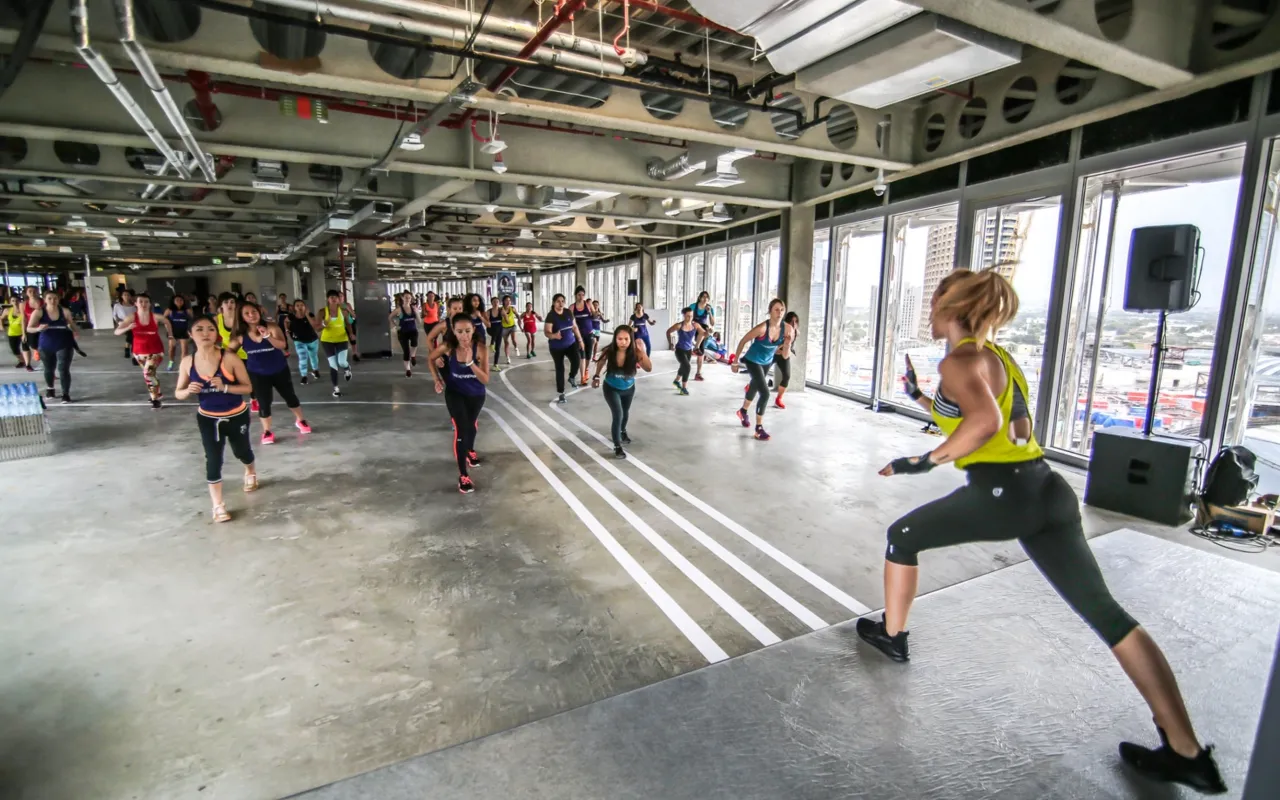 Instructor leads a large cardio class inside the sunlit industrial venue