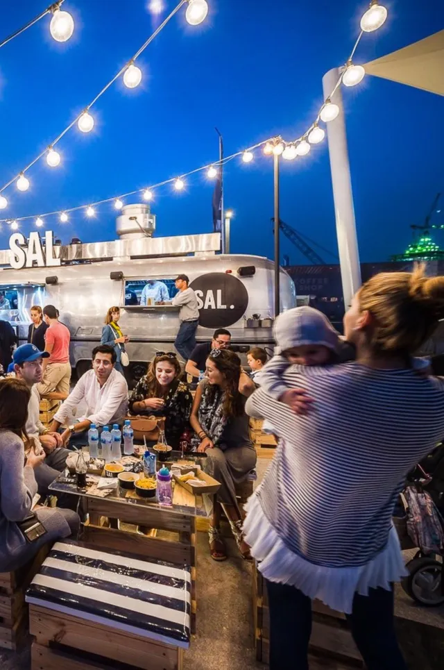 Guests share evening meals beneath string lights at the festival