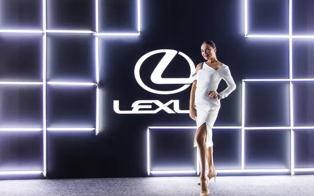 Event hostess stands before the illuminated Lexus backdrop