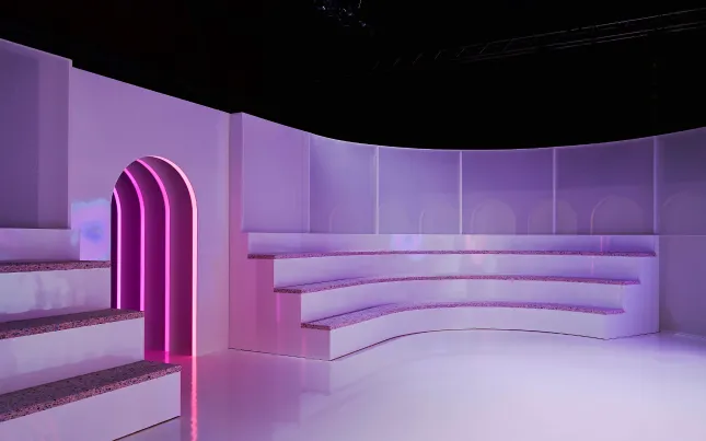 Tiered white presentation seating with a magenta arched entrance