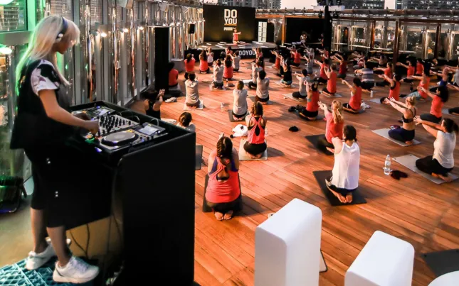 DJ performs beside a seated rooftop fitness class