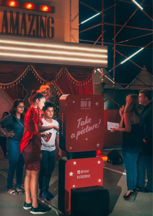 Guests pose at an illuminated outdoor photo booth installation