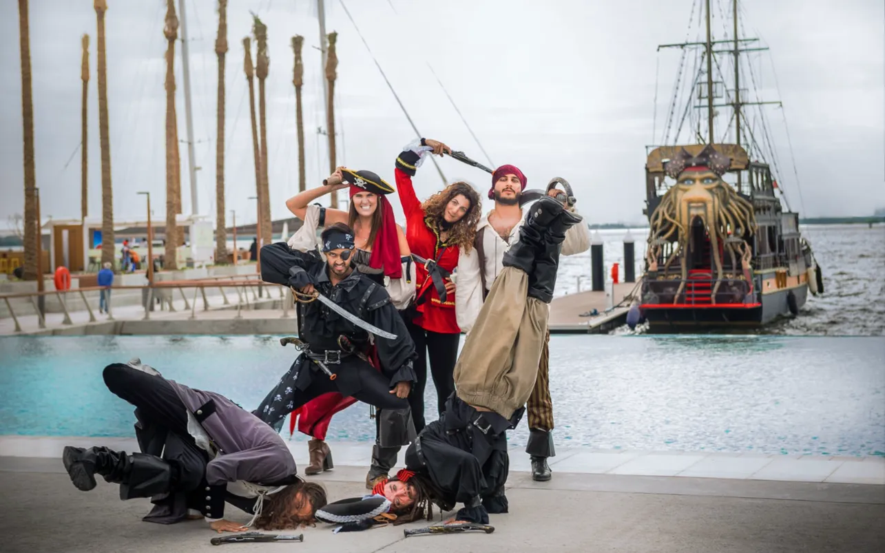 Costumed pirates perform beside a waterfront pirate ship