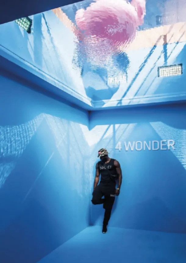 Guest explores an immersive blue projection room beneath a mirrored ceiling