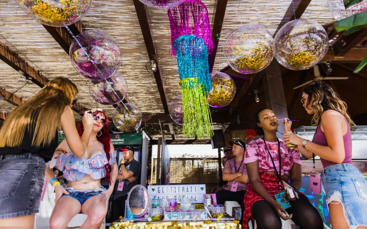 Guests receive glitter makeup at a vibrant festival beauty bar