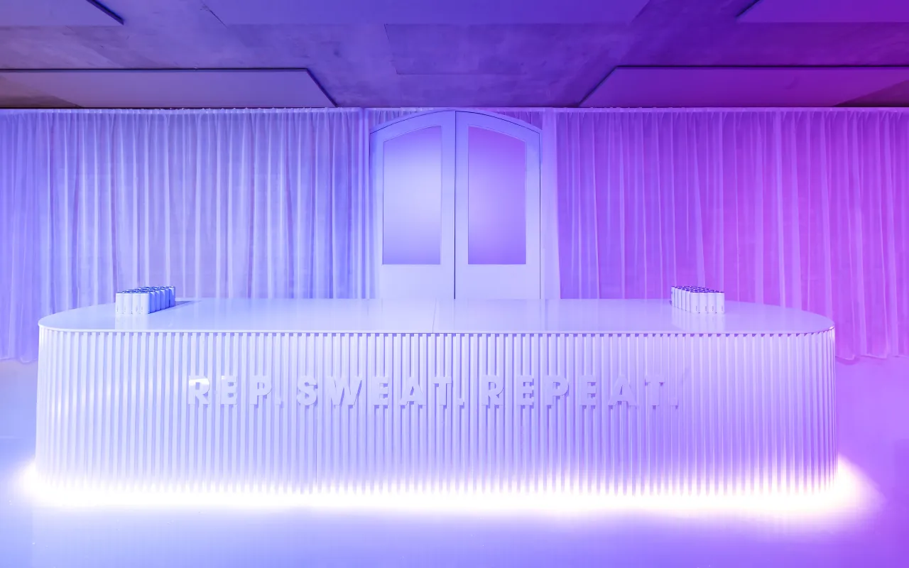 White ribbed reception desk illuminated in blue and magenta