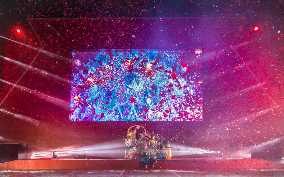 Performers celebrate beneath red confetti on the Lexus Drive-In stage