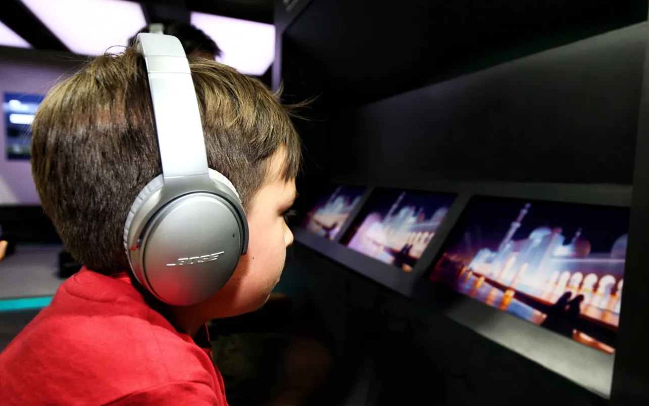 Child wears headphones while exploring an interactive digital display