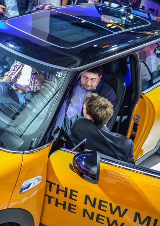 Guest sits inside an orange MINI while an event host assists