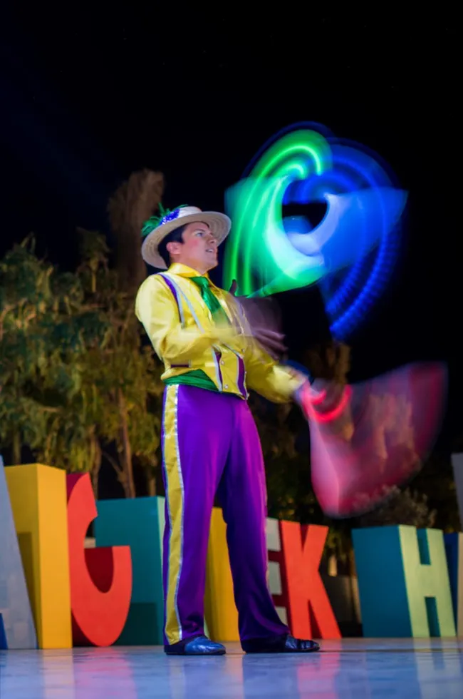Colorful juggler spins glowing hoops during the nighttime community festival