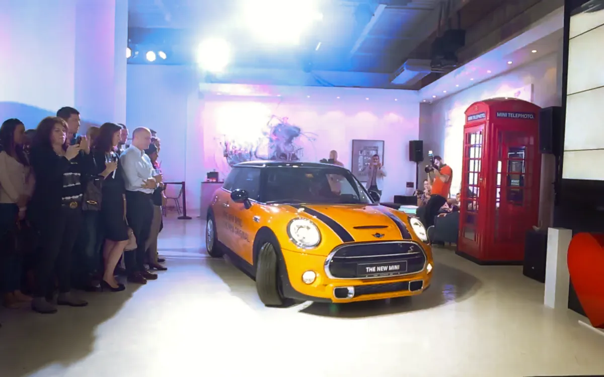 Orange MINI Cooper enters the launch venue before assembled guests