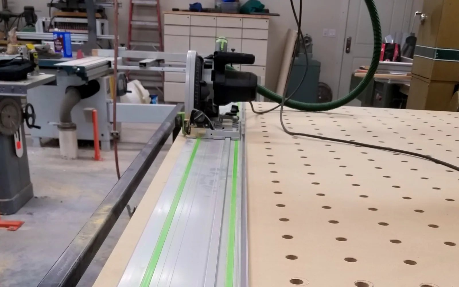 Track saw positioned beside a perforated wood panel in the workshop